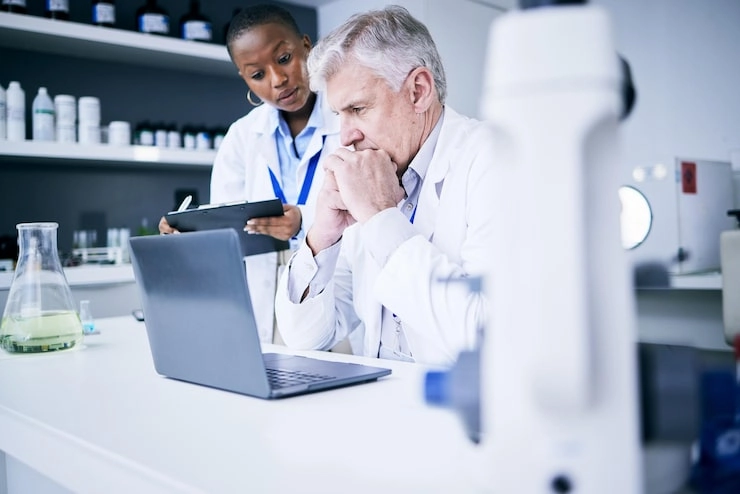 Two researchers (a male scientist and a female colleague in lab coats) collaborating in a laboratory